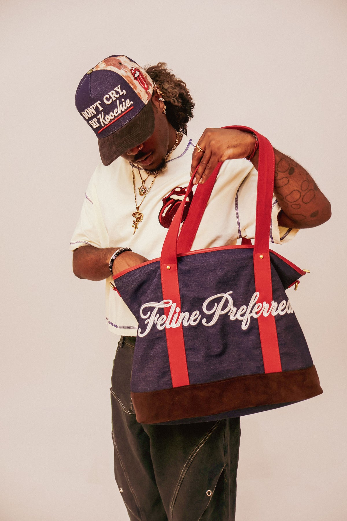Model carrying the indigo denim Feline Preferred tote by its red handles