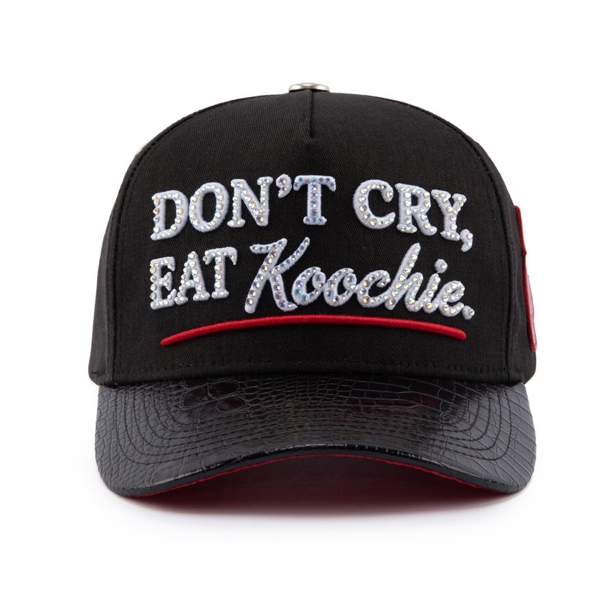 Black Goddess V3 hat, front: black crown with rhinestone-set Don't Cry, Eat Koochie lettering, red underline and black snake-texture brim